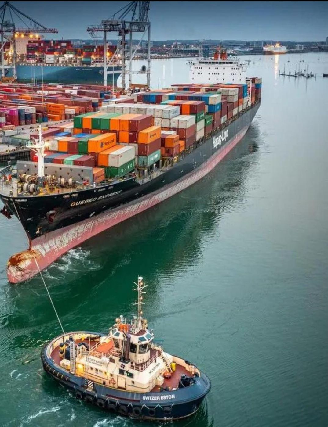 Kapal kontainer dipandu kapal tunda di pelabuhan